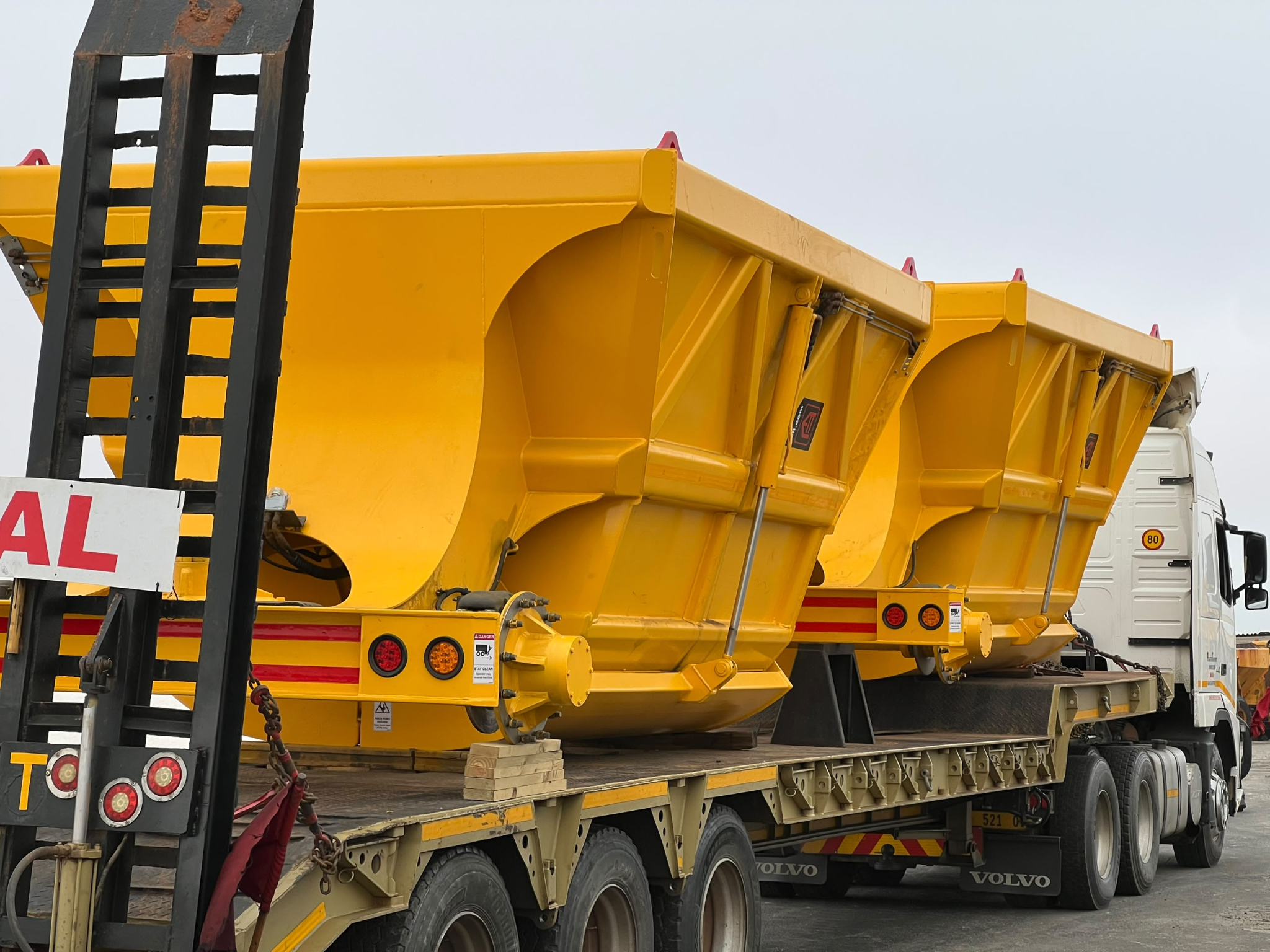 Large yellow load bodies carried on a lowbed trailer
