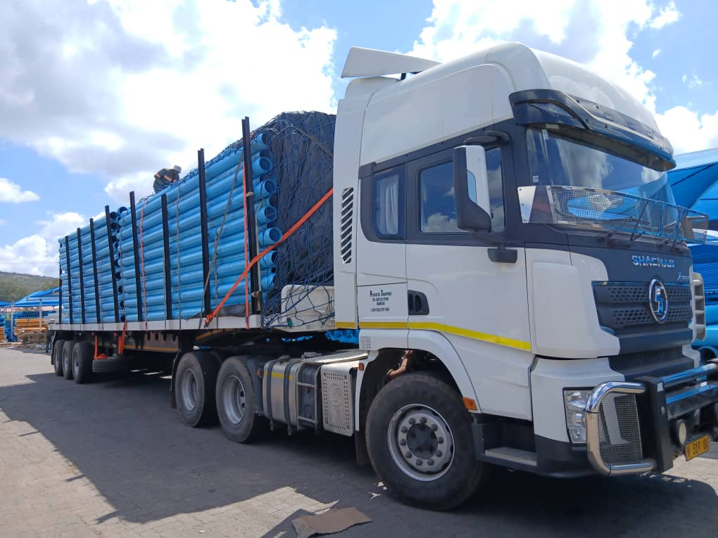Truck carrying secured blue pipes