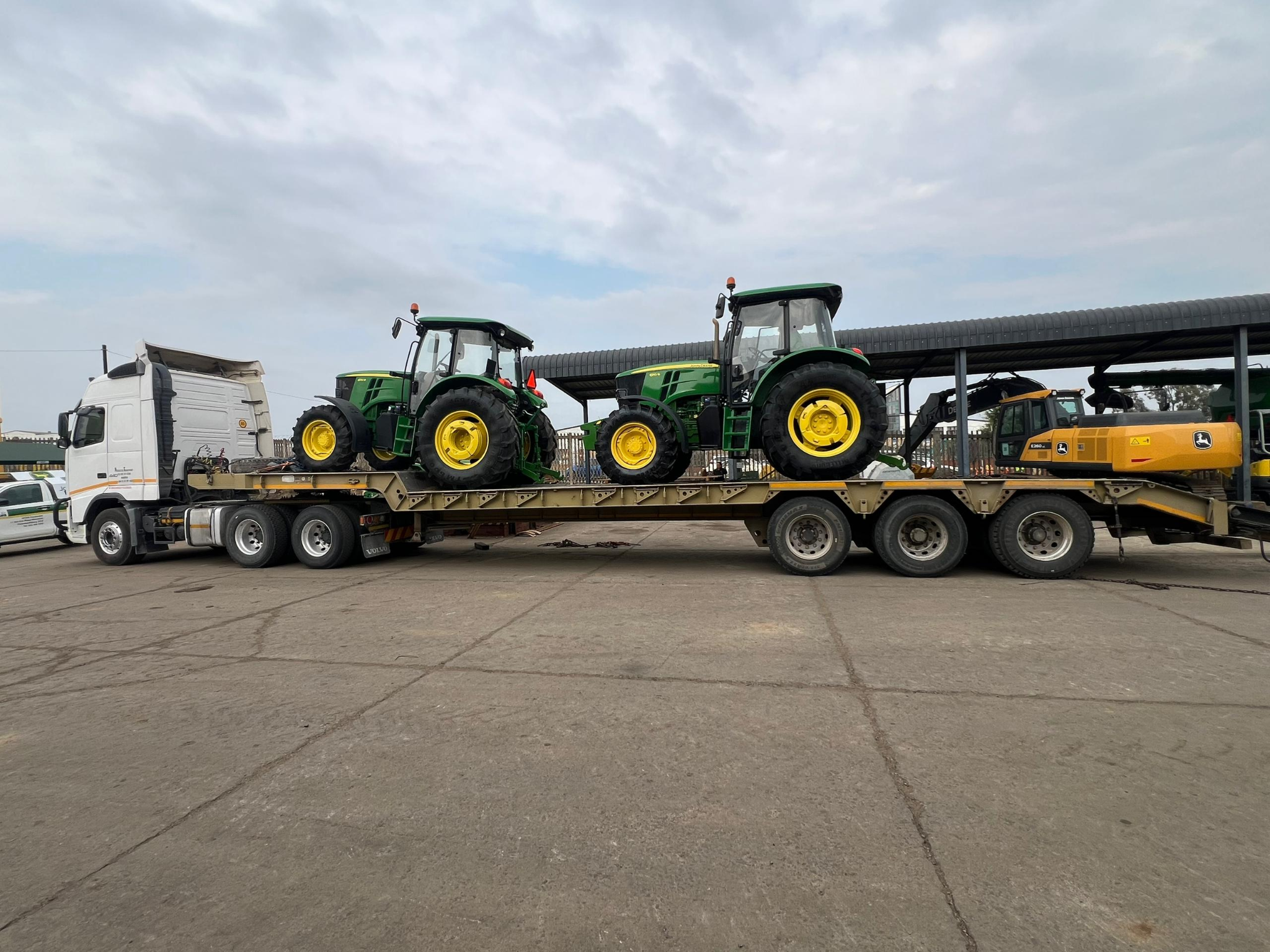 Two green tractors secured on a transport trailer
